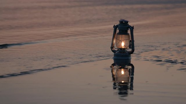 Old vintage kerosene lantern on beach at sunset