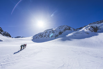 Skitouring in Oetztal. Beautiful day, sun shining, sun star, alpinists and ski alpinist touring on...