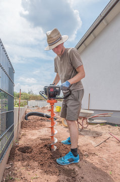 Mann gr&auml;bt Fundamente mit Erdlochbohrer