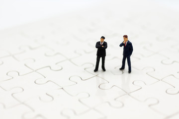 Miniature people : Businessman standing on jigsaw board. Image use for to solve problems, finding solution and think new idea concept.