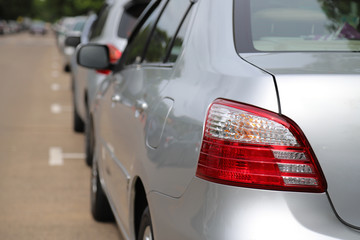 Closeup of left rear side of bronze car parking beside the street in sunny day.
