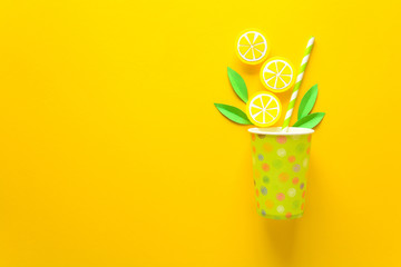 Summer drink with paper cut lemon slices and leaves on yellow paper background. Summer drink concept. Top view. Flat lay