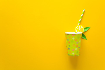 Summer drink with paper cut lemon slices and leaves on yellow paper background. Summer drink concept. Top view. Flat lay