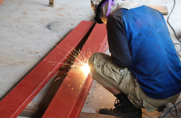 Closeup of worker cutting metal with electric cutter on cement floor.