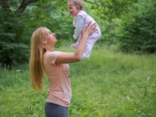 Young mother playing with baby girl outdoor in summer day