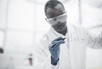 confident scientist writing a structural formula on a glass Board