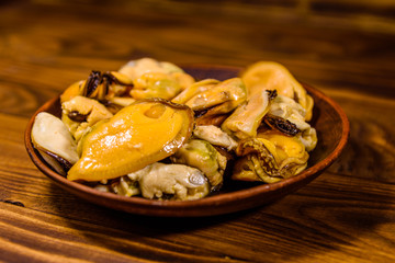 Ceramic plate with prepared mussels on wooden table
