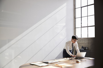 Businessman working alone using laptop in bare office