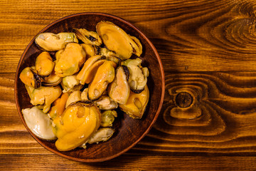 Ceramic plate with prepared mussels on wooden table. Top view