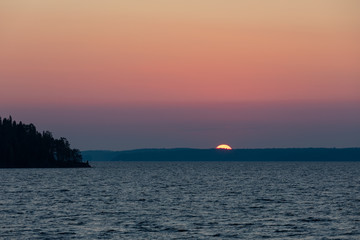 Fototapeta na wymiar Big red sun rising over lake scene