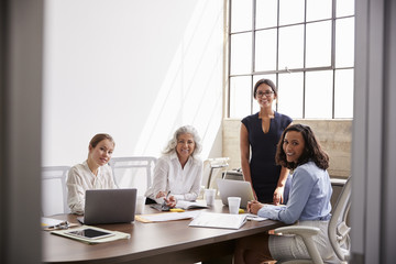 Four businesswomen look to camera,  seen from doorway