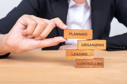 business hand putting the wooden toy with words about four functions of management: Planning, Organizing, Leading and Controlling for business and management concept