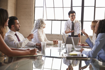 Asian businessman addressing colleagues in meeting, close up