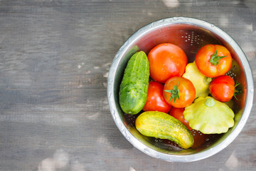 Tomato, cucumber, zucchini, patisson in an iron pan on a wooden table. Concept of a healthy diet, dietetic vegetables. Harvesting