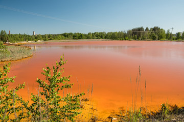 A pond with bright red water. environmental problems, pollution of the environment.
