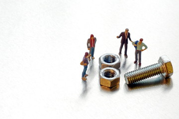 Miniature figures of businessmen discuss the problem with bolt and nuts. The concept of collective solution. Brainstorming.