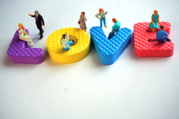 Miniature figures of men and women sit on the colored letters of the word love. The concept of the relationship between a man and a woman.