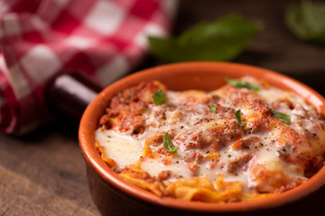 Traditional lasagne in a casserole dish on wooden table