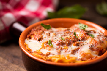 Traditional lasagne in a casserole dish on wooden table
