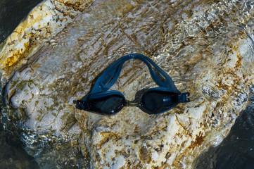 eyeglasses for swimming on a pebble beach in the sea waves