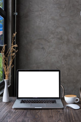 blank screen laptop computer with latte art coffee on wooden table, dark background