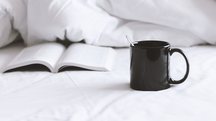a coffee cup and a book on bed