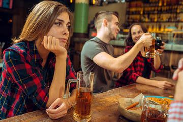 people, leisure, friendship and communication concept - happy friends drinking beer, talking and clinking glasses at bar or pub