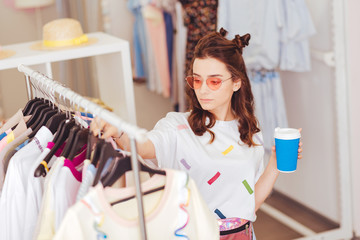 Cup of coffee. Modern young woman being real shopaholic holding cup of coffee coming to showroom