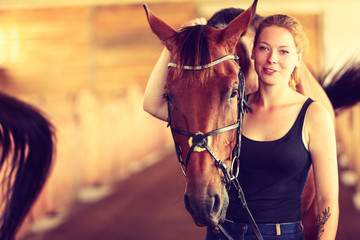 Young woman girl in stable with horse.