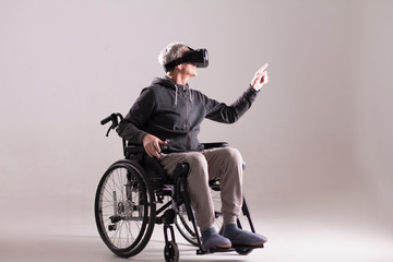 Studio shot of man in wheelchair wearing VR goggles. Disabled man in wheelchair wearing formal suit...