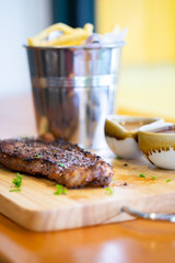 Steak with fries and sauce on a wooden tray