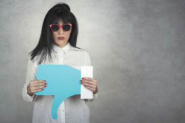 Young Woman holding a dislike icon on gray background