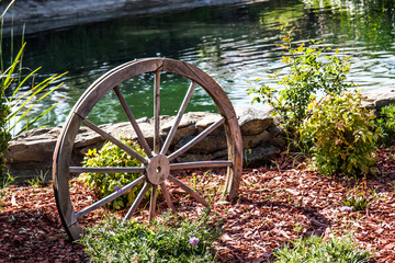 Vintage Wooden Wheel In Garden Next To Pond