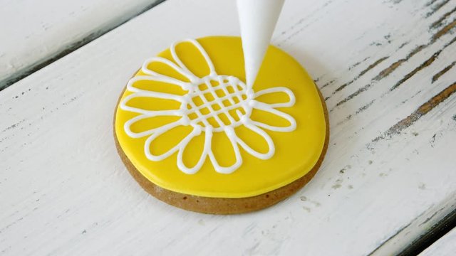 Decoration of yellow cookie with white flower. Cut out sugar cookie with frosting. Decorating cookies technique.