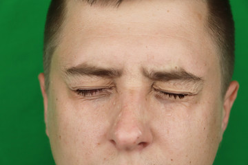 Obraz premium Tears in eyes of crying adult man. Green background. Chromakey