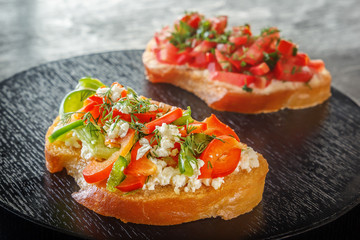 Bruschetta with red sweet pepper and goat cheese on a black background. Close-up