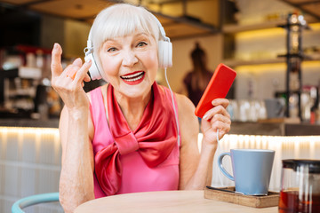 Wonderful song. Cheerful positive woman wearing headphones while enjoying listening to the rock...