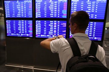 Fototapeta premium Traveling man waiting for a flight at airport late at night, businessman using mobile phone. Transit, Connecting flihgts
