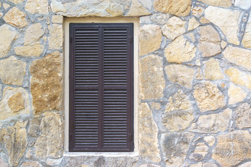 Fototapeta na wymiar Window with blinds in the stone wall