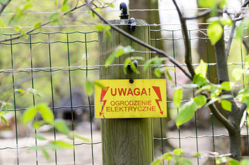 Warning sign with a live fence in polish language (uwaga ogrodzenie elektryczne pod napieciem).