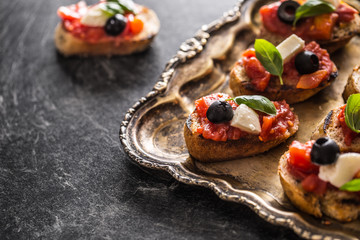 Bruschetta toast with mozzarella tomatoes olives and basil.