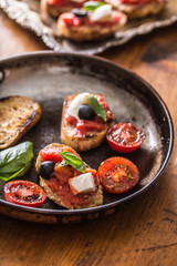 Bruschetta toast with mozzarella tomatoes olives and basil.