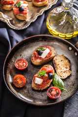 Bruschetta toast with mozzarella tomatoes olives and basil.