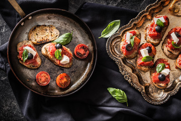 Bruschetta toast with mozzarella tomatoes olives and basil.