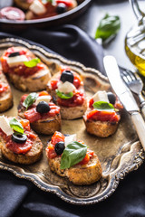 Bruschetta toast with mozzarella tomatoes olives and basil.