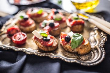 Bruschetta toast with mozzarella tomatoes olives and basil.