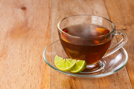 a cup of lime tea on wooden table, hot drink with steam