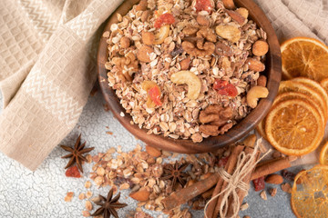 Wooden Bowl with granola with nuts, dried crandberries and dried orenge on a old light table