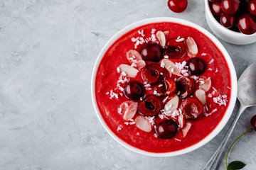Red cherry smoothie with fresh berries, almond flakes and coconut chips.