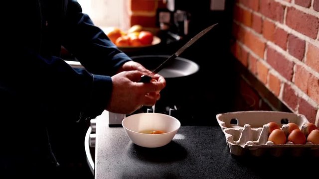 Male hands breaking eggs on bowl in the kitchen

